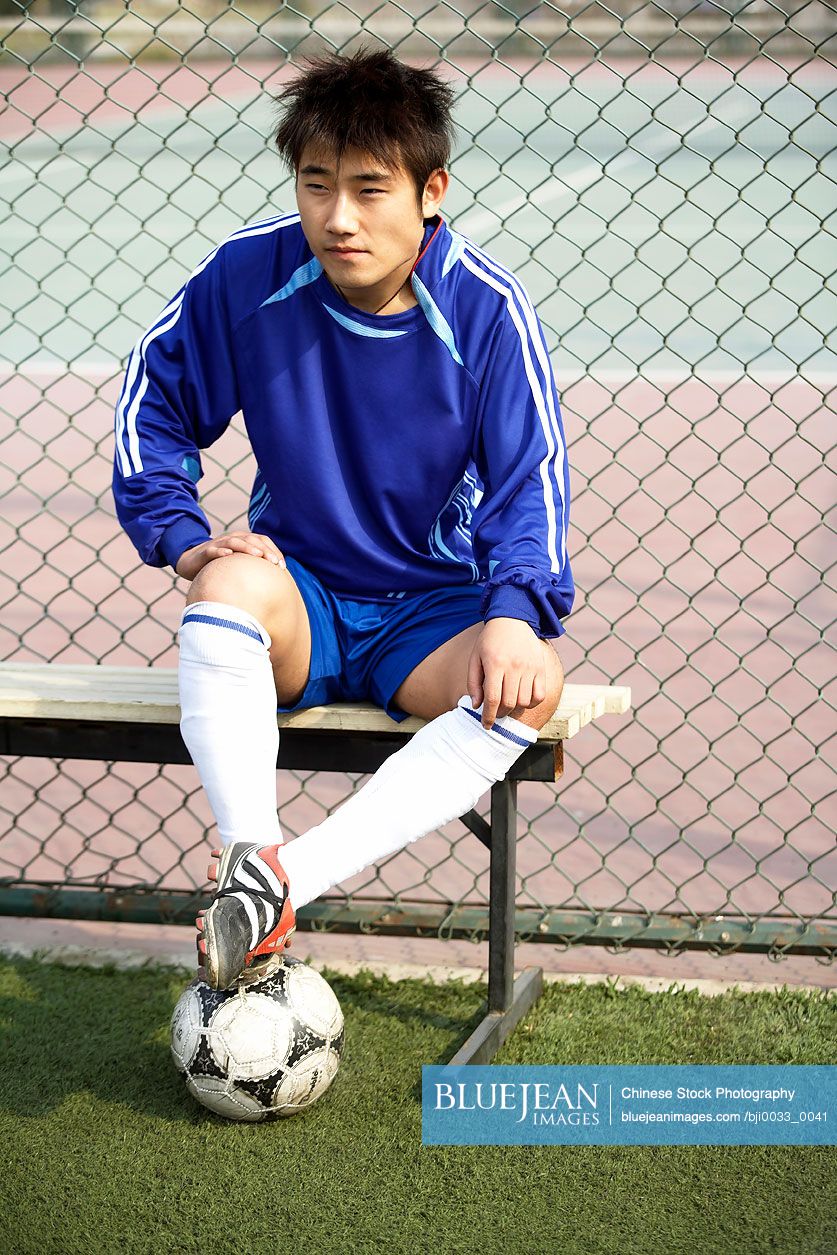 Young Chinese Soccer Player Sitting On Bench