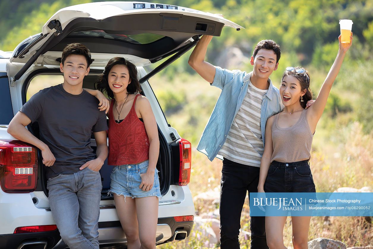 Happy young Chinese friends enjoying road trip