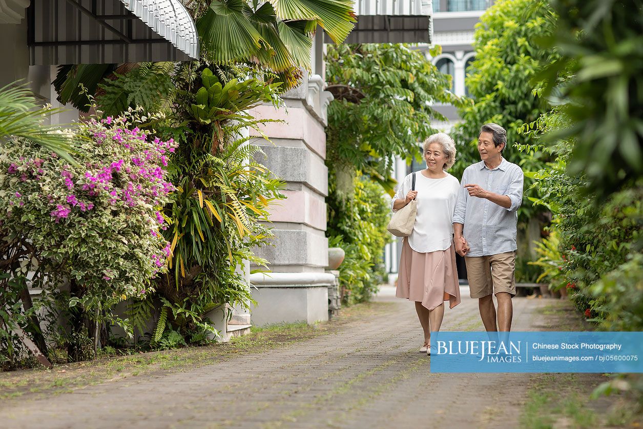 Happy senior Chinese couple holding hands and walking together
