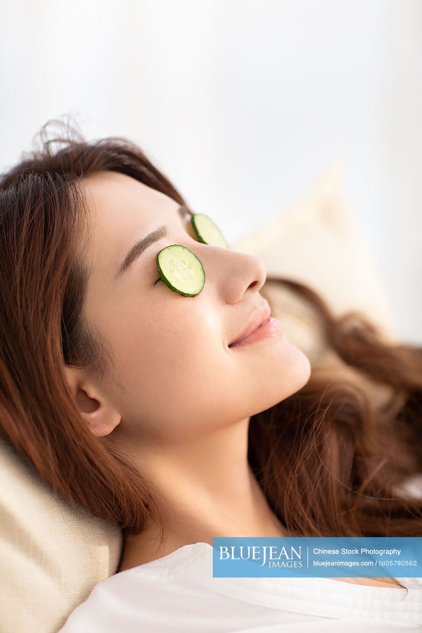 Young Chinese woman with cucumber slices on face