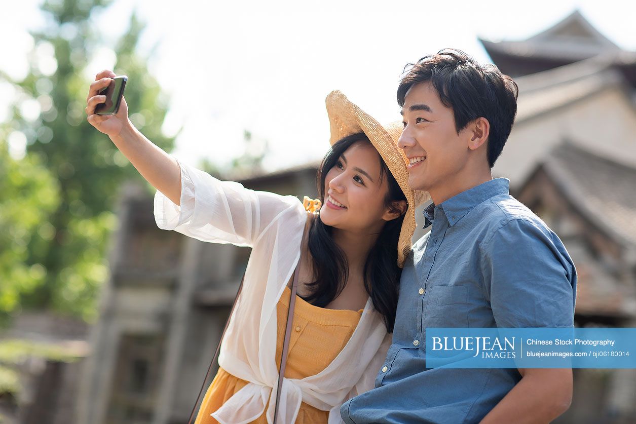 Happy young Chinese couple taking selfie outdoors