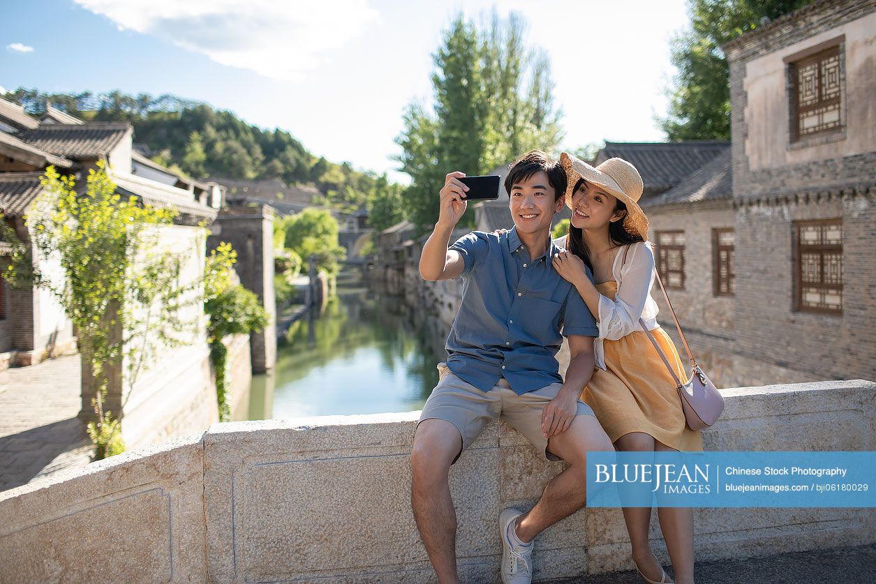 Happy young Chinese couple taking selfie outdoors