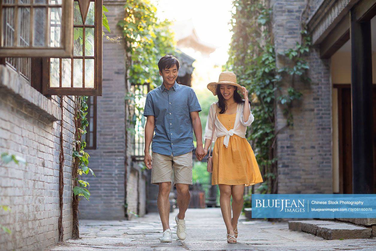 Happy young Chinese couple walking in alley