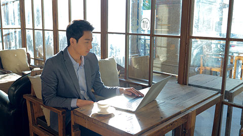 Young Chinese businessman using laptop in coffee shop,4K