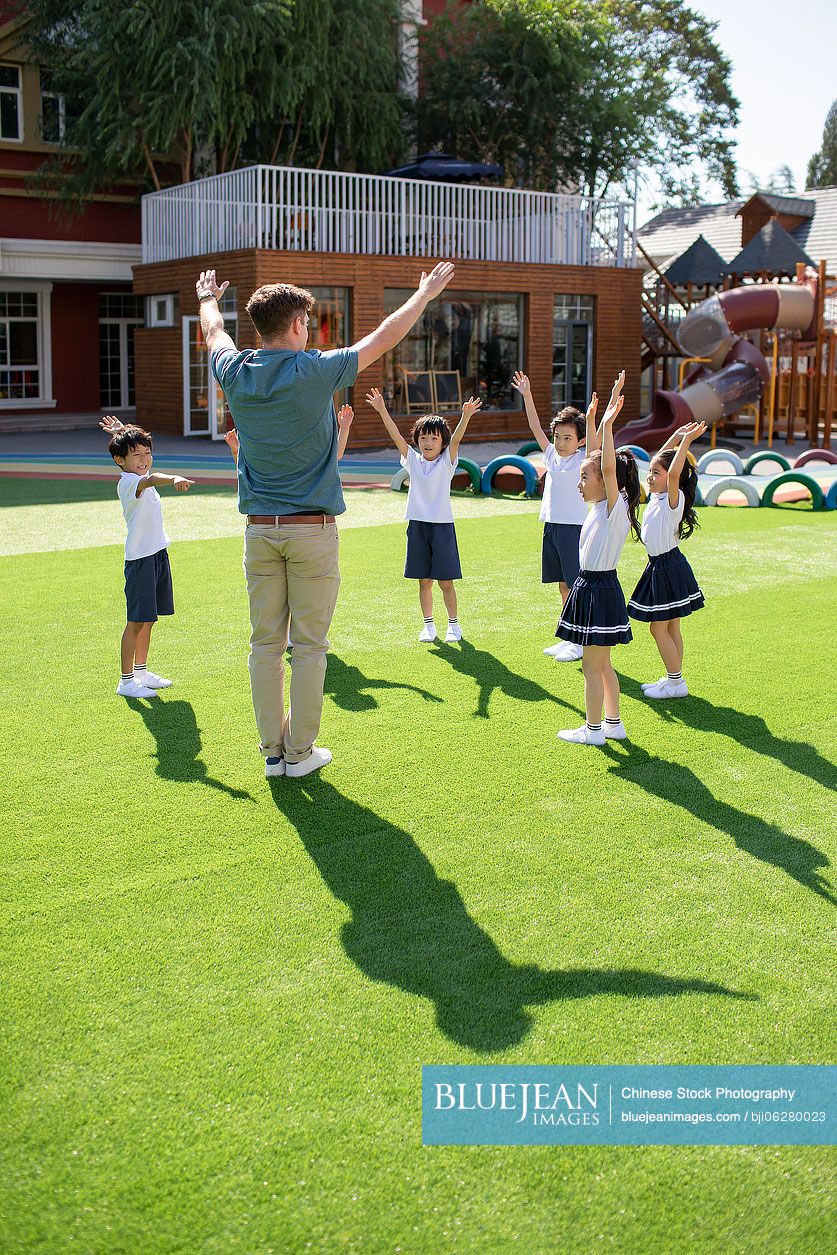 Foreign teacher and children playing in kindergarten playground
