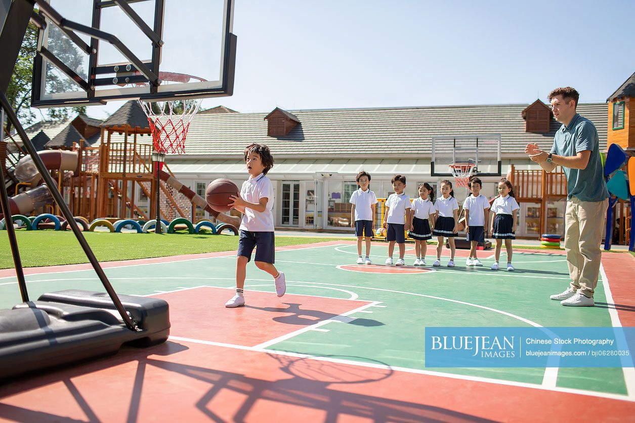 Foreign teacher and children playing basketball in playground
