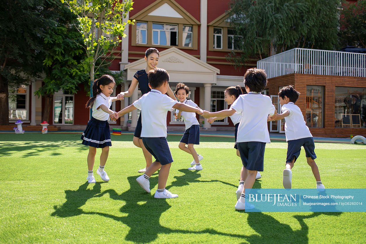 Chinese teacher and students playing in kindergarten playground