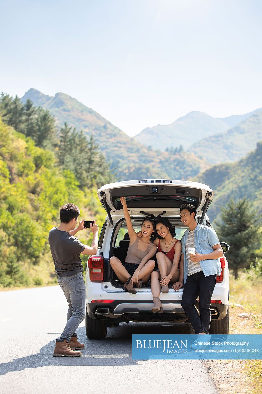 Happy young Chinese friends enjoying road trip