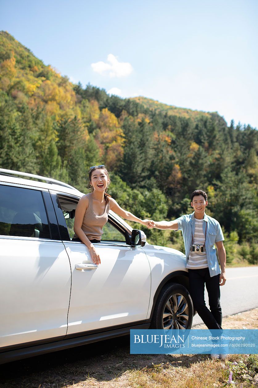 Happy young Chinese couple enjoying road trip