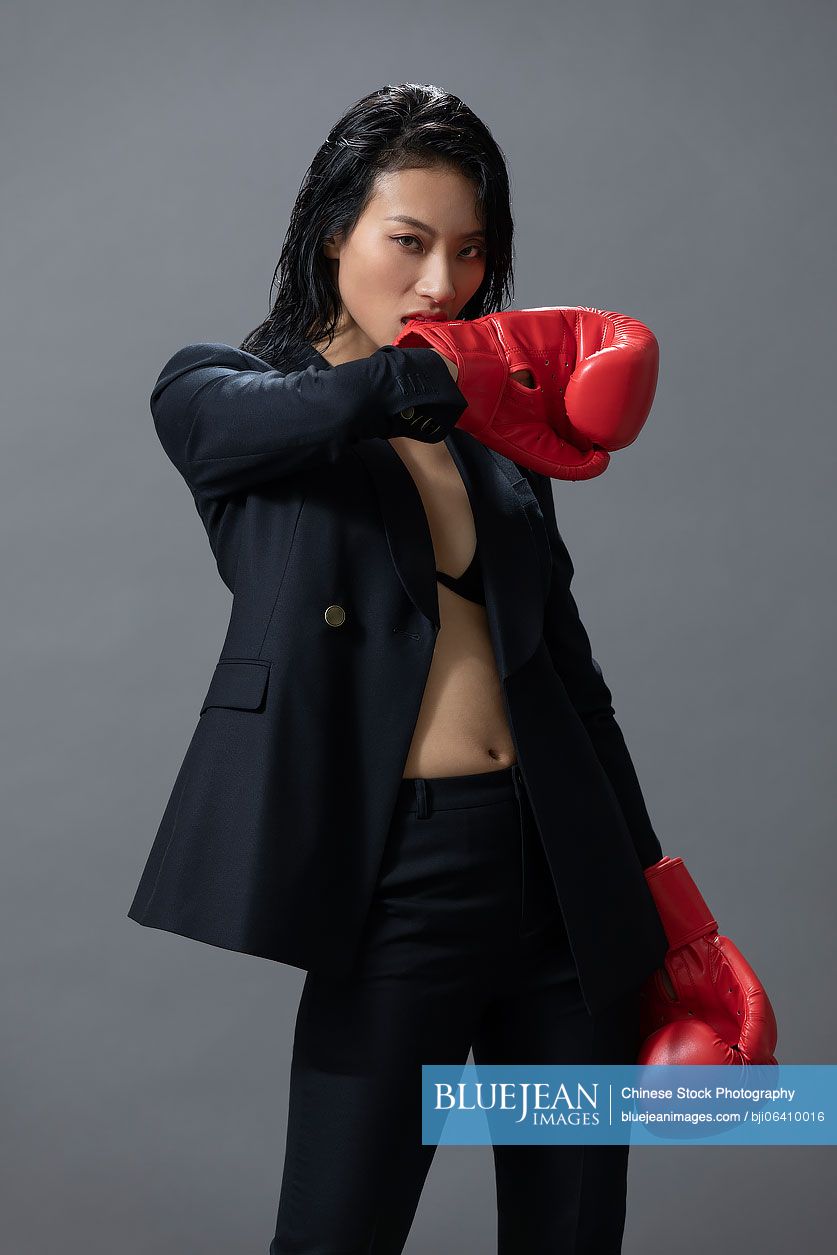 Cool young Chinese woman wearing boxing gloves