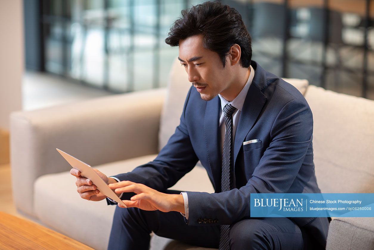 Successful Chinese businessman using digital tablet
