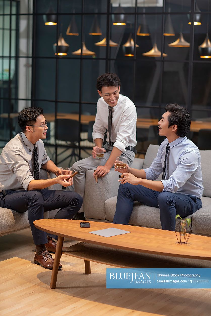 Successful Chinese businessmen drinking alcohol in office