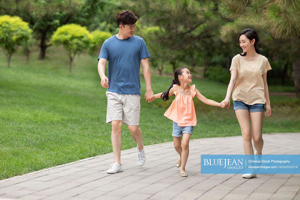 Happy young Chinese family walking in park