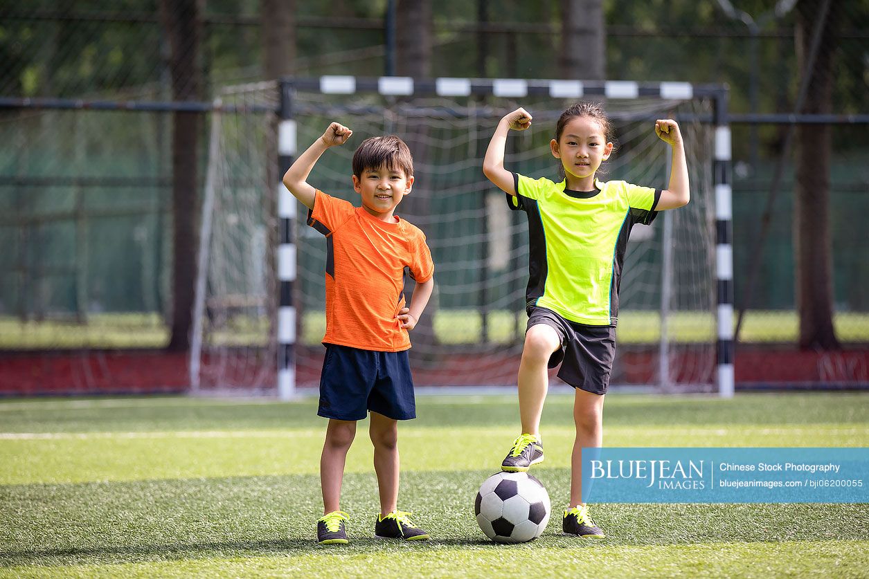 Happy Chinese children playing football on field