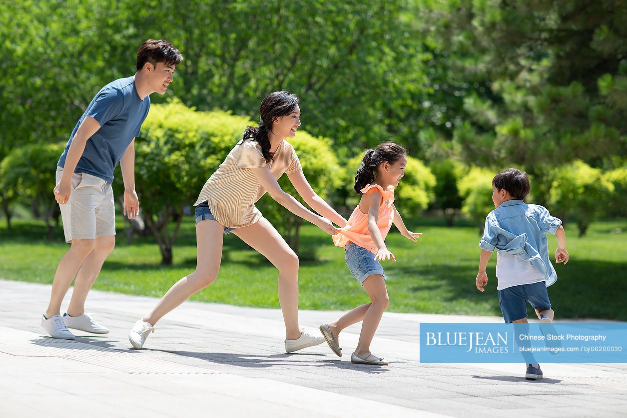 Happy young Chinese family having fun in park