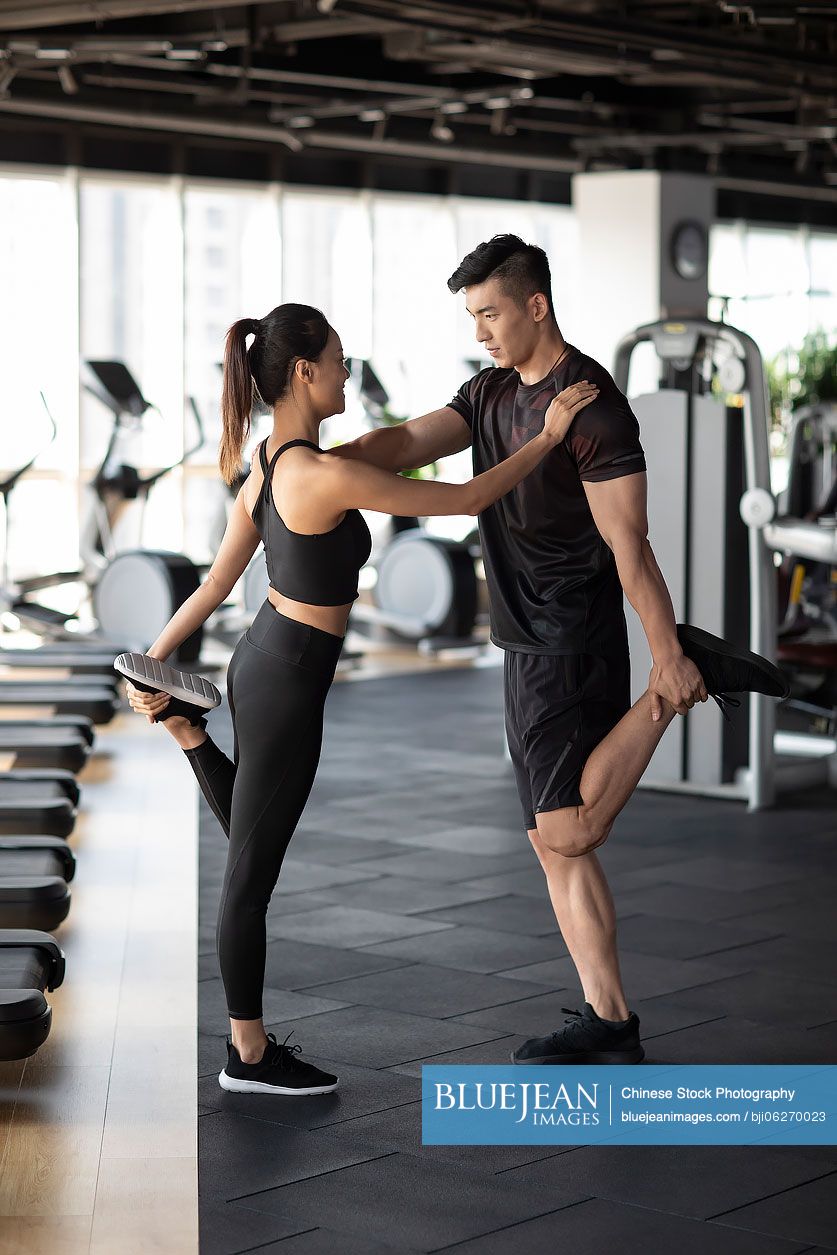 Young Chinese woman working out with personal trainer at gym-High