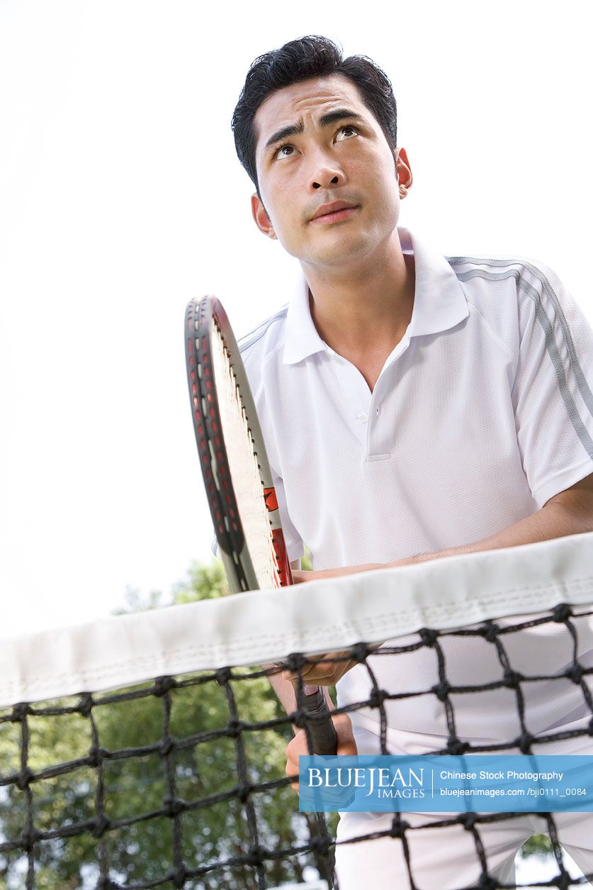 Young Chinese man playing tennis