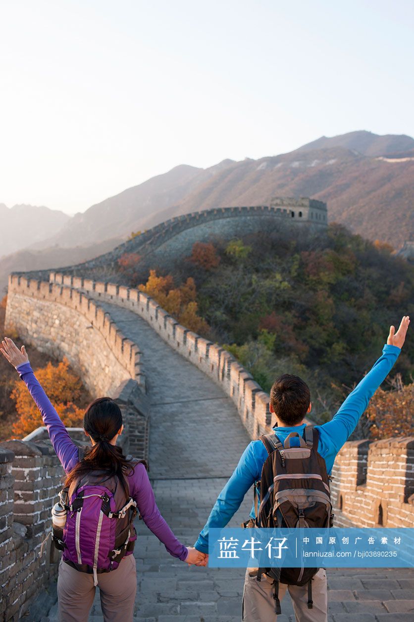 年轻情侣在长城上挥手