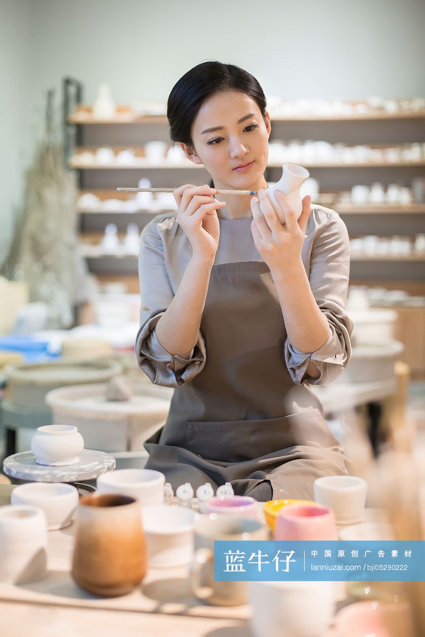 年轻陶艺师给陶胚上色