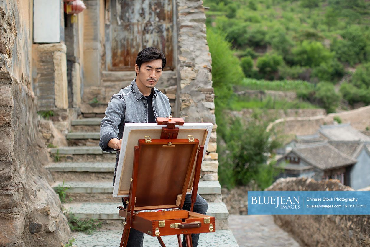 Young Chinese artist painting outdoors