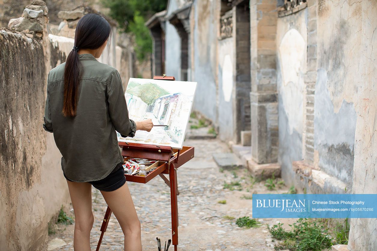 Young Chinese artist painting outdoors