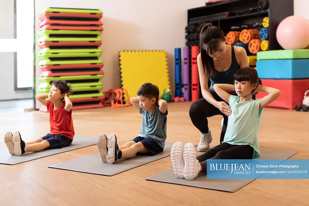 Cute Chinese children having exercise class in gym