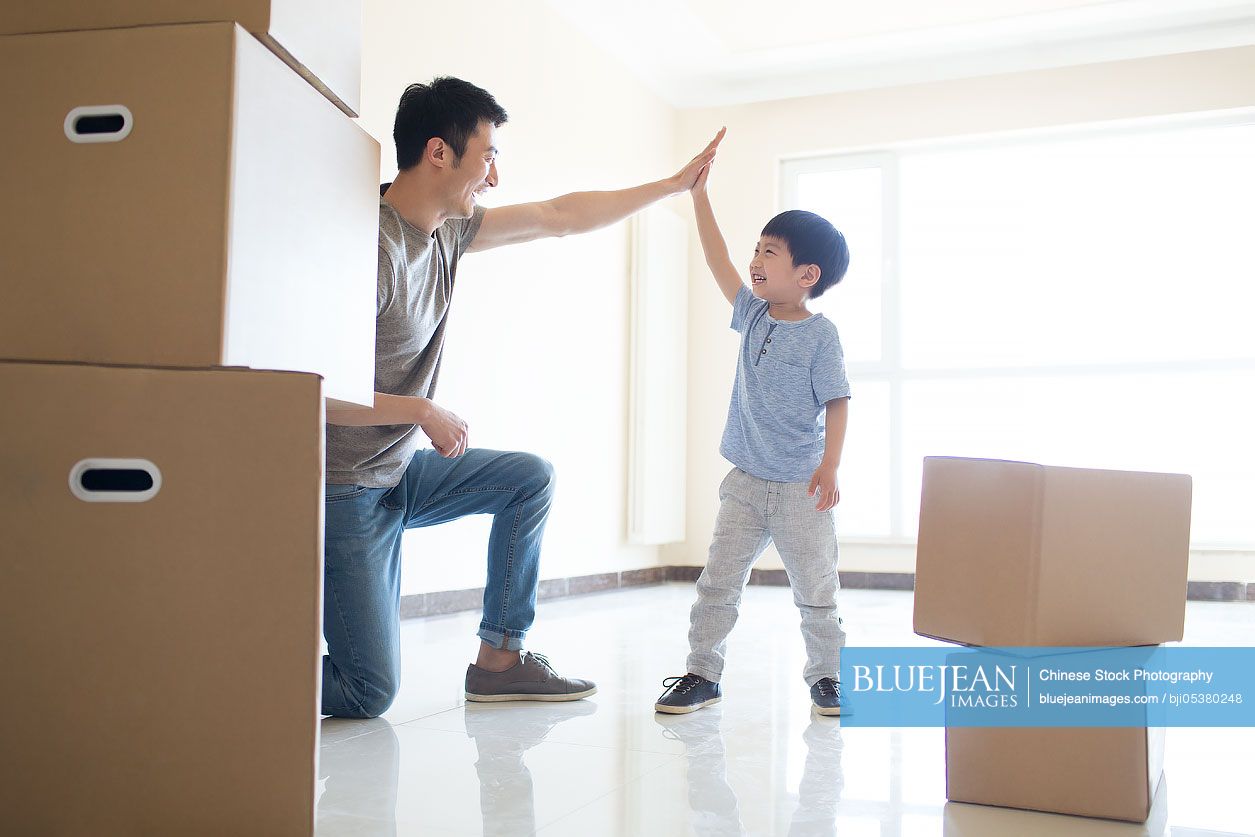 Happy young Chinese father and son moving home