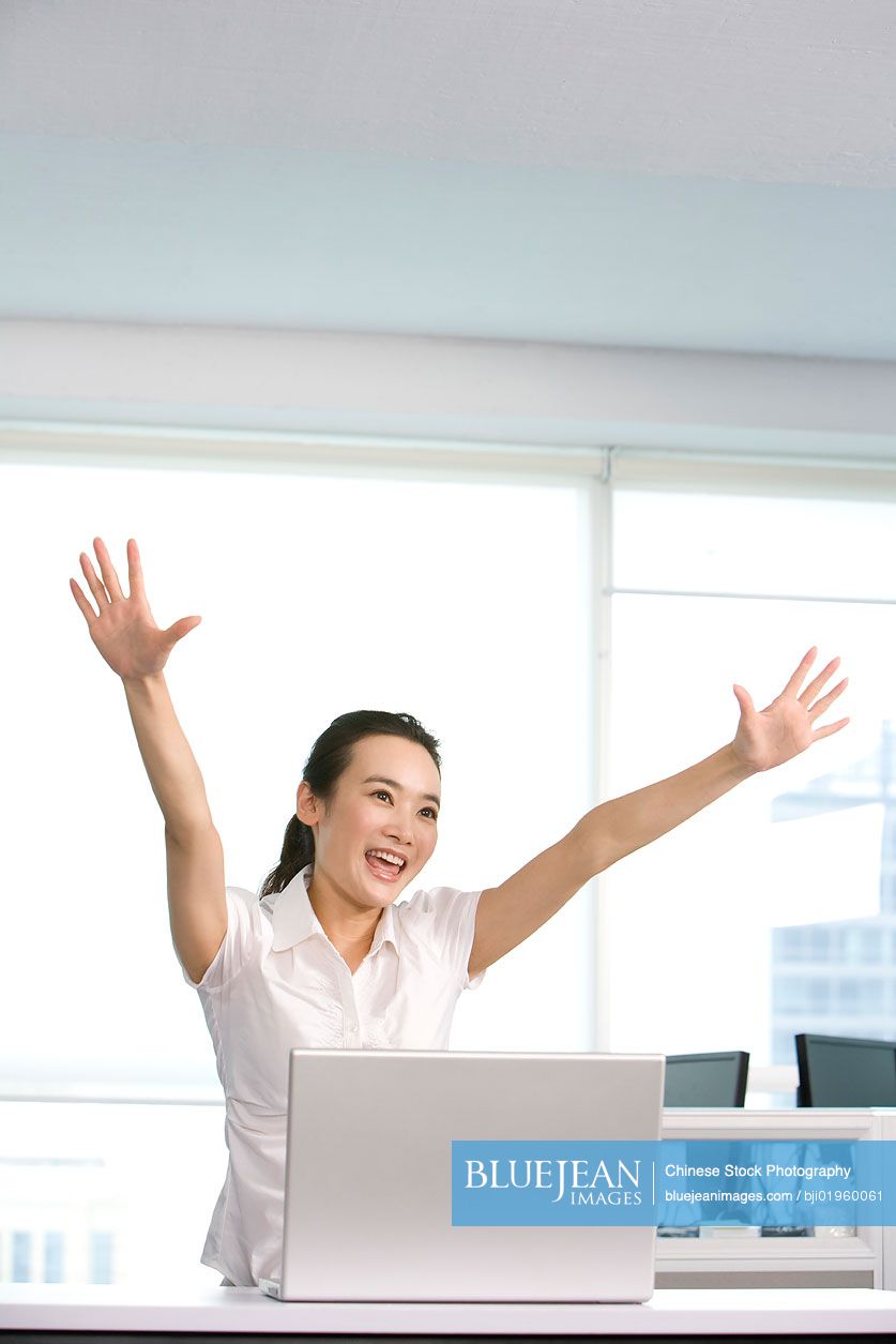 Happy Chinese office worker at her desk