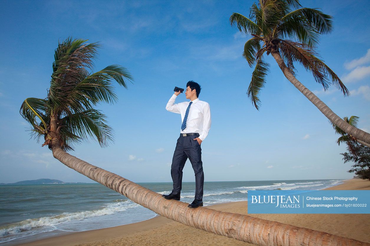 Chinese businessman looking off into the distance with binoculars