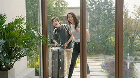 Happy young Chinese couple entering hotel room with suitcase,4K