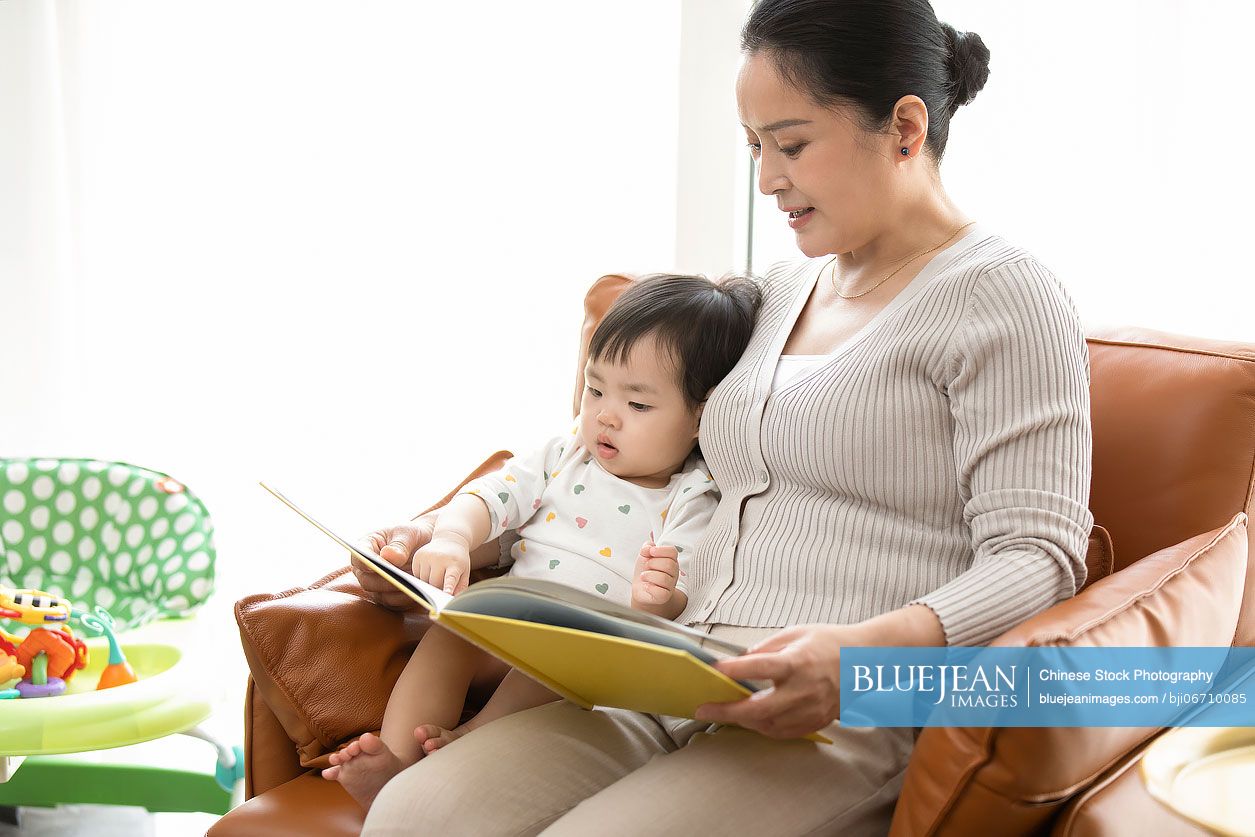 Happy Chinese grandmother and baby reading picture book