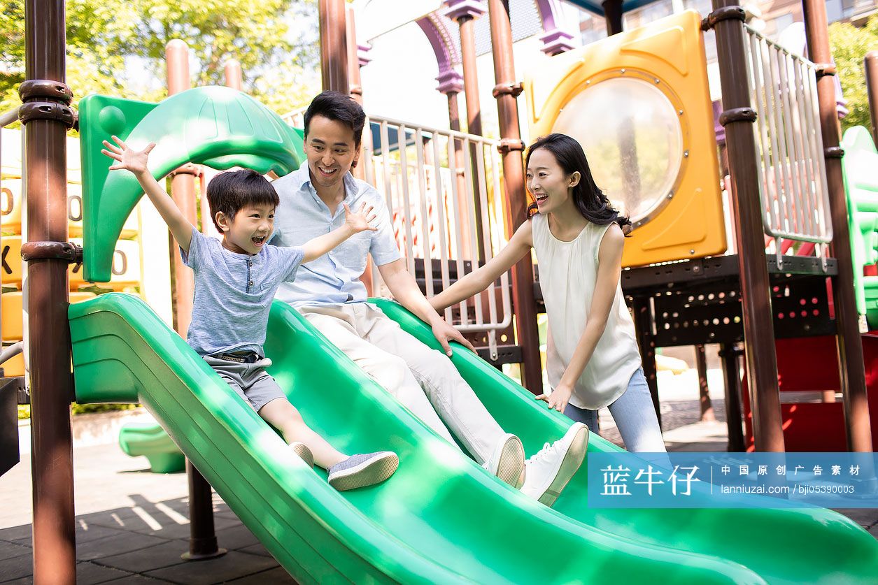 年轻家庭在游乐园滑滑梯