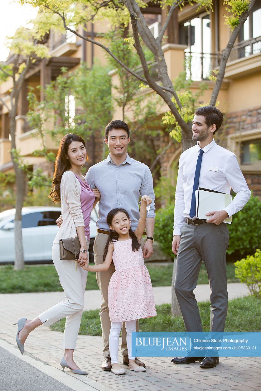 Happy young Chinese family receiving house key from real estate agent