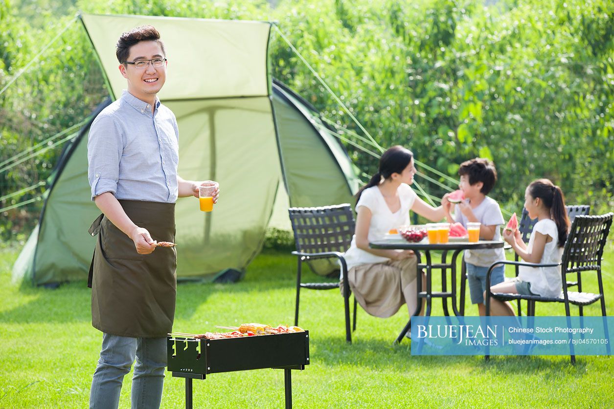 Young Chinese family barbecuing outdoors