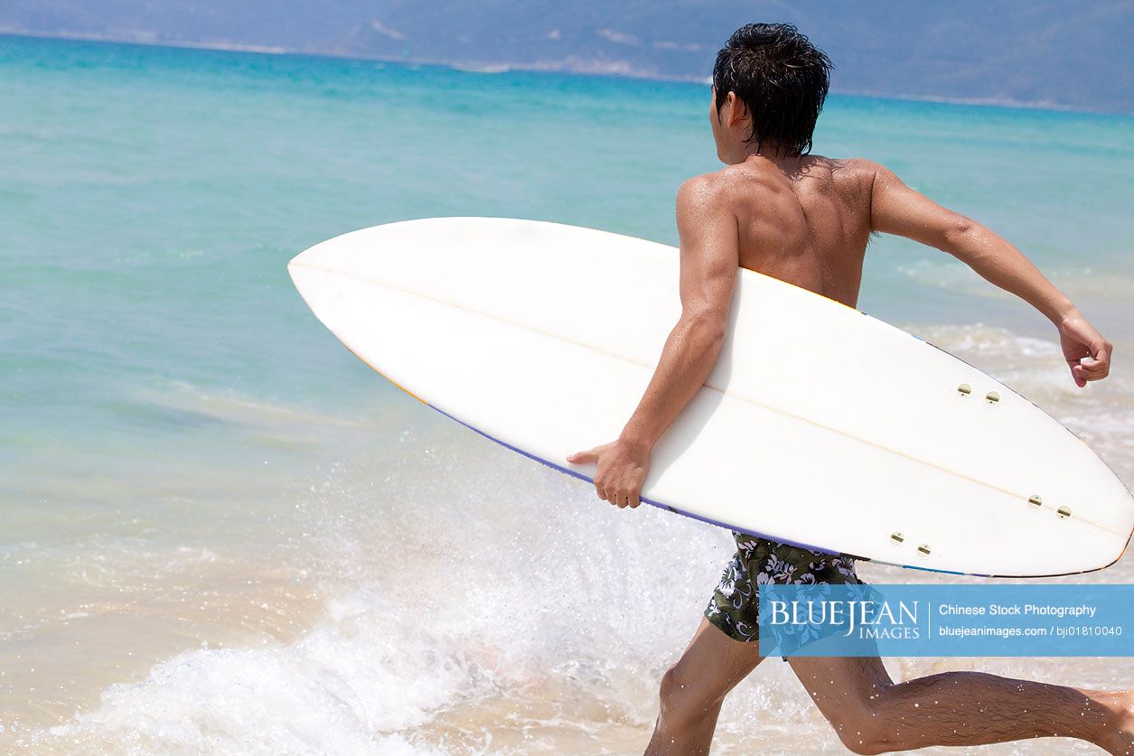 Portrait of a young Chinese man with a surfboard