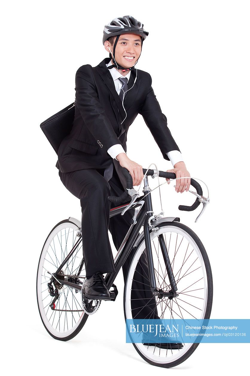 Happy young Chinese businessman cycling to work