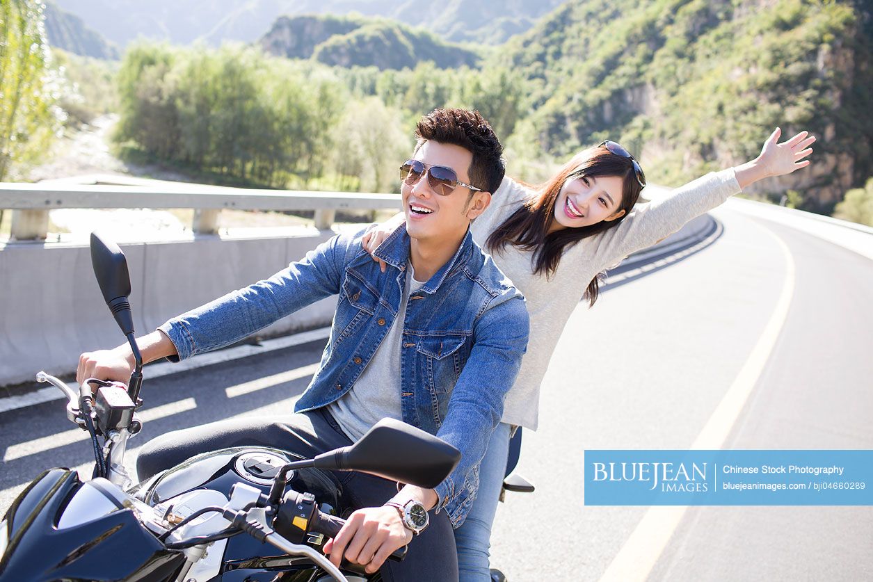Young Chinese couple riding motorcycle together