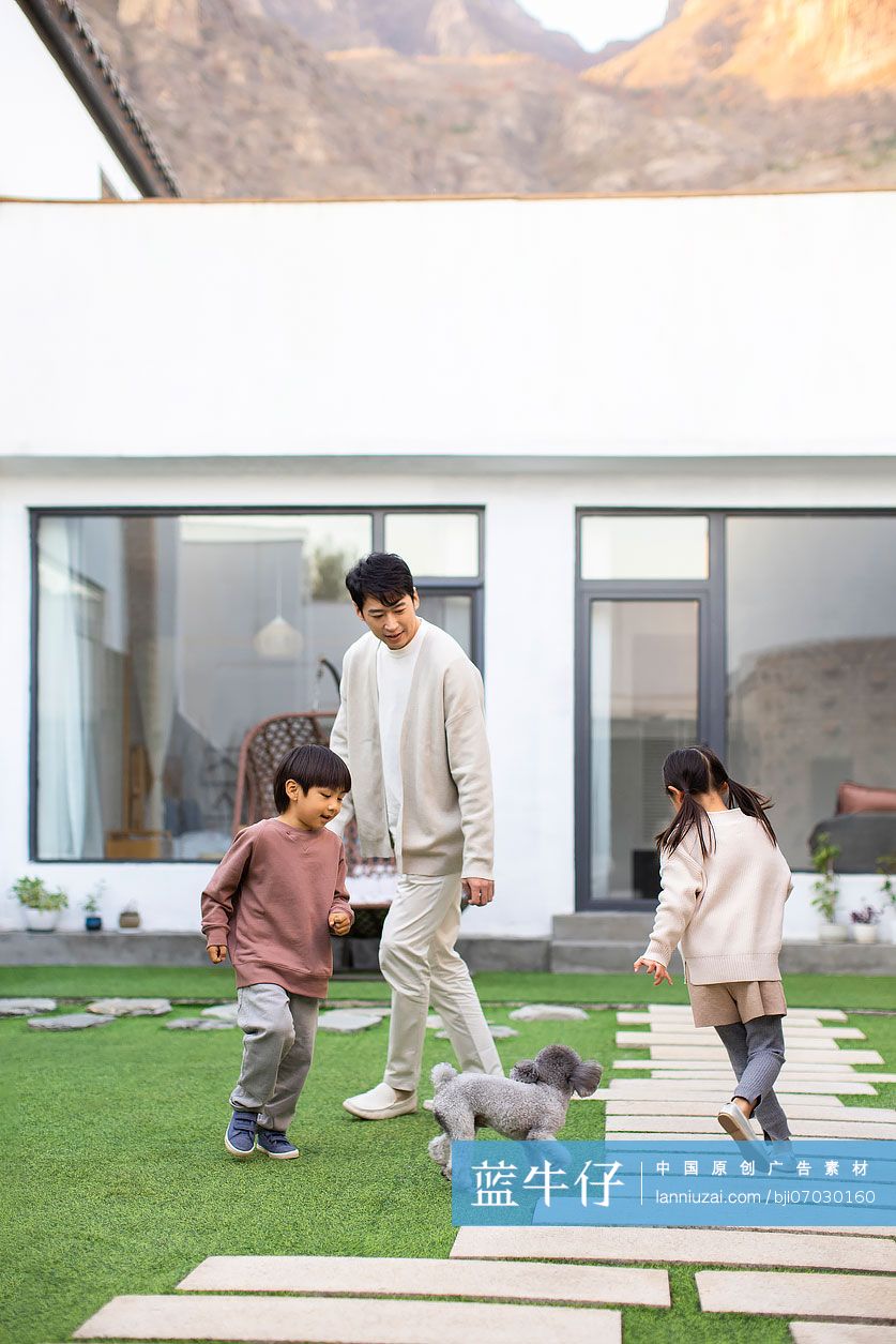 快乐的年轻家庭和宠物狗在庭院里玩耍