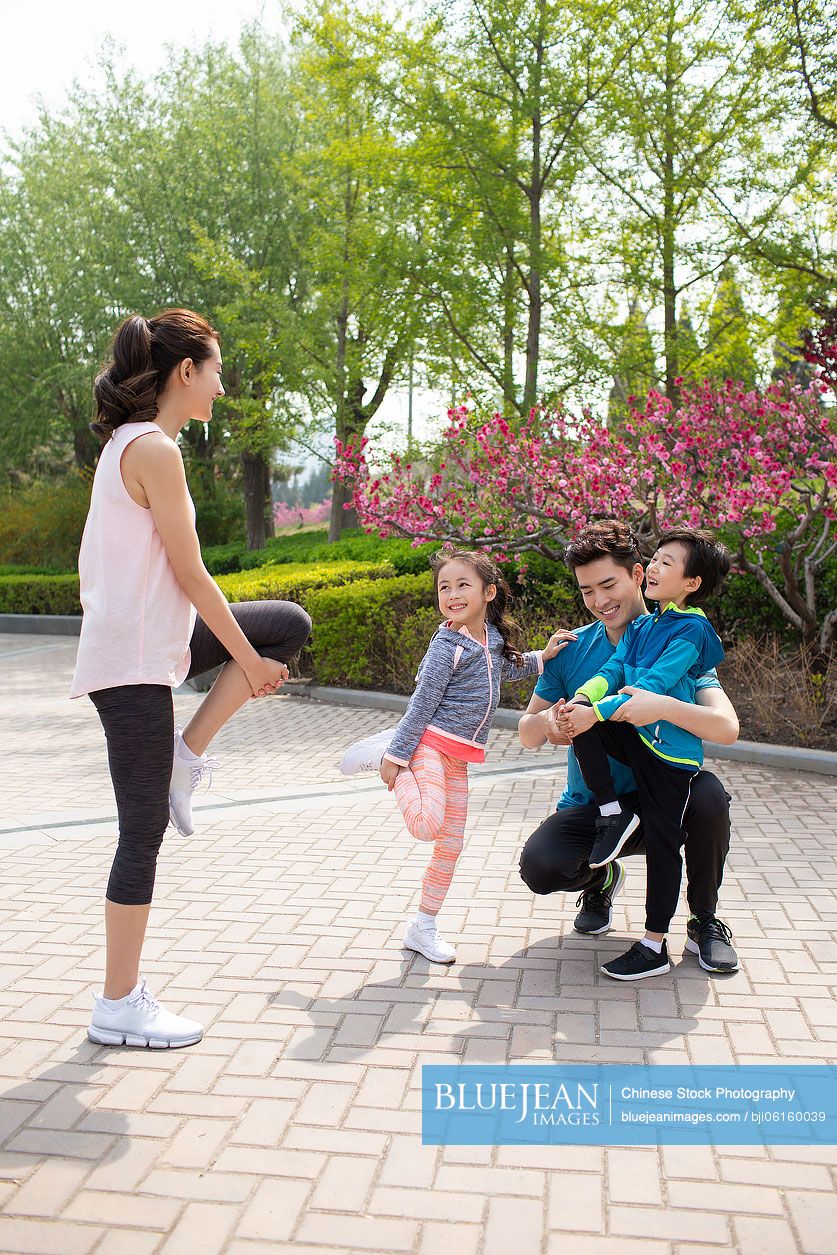 Happy young Chinese family exercising in park