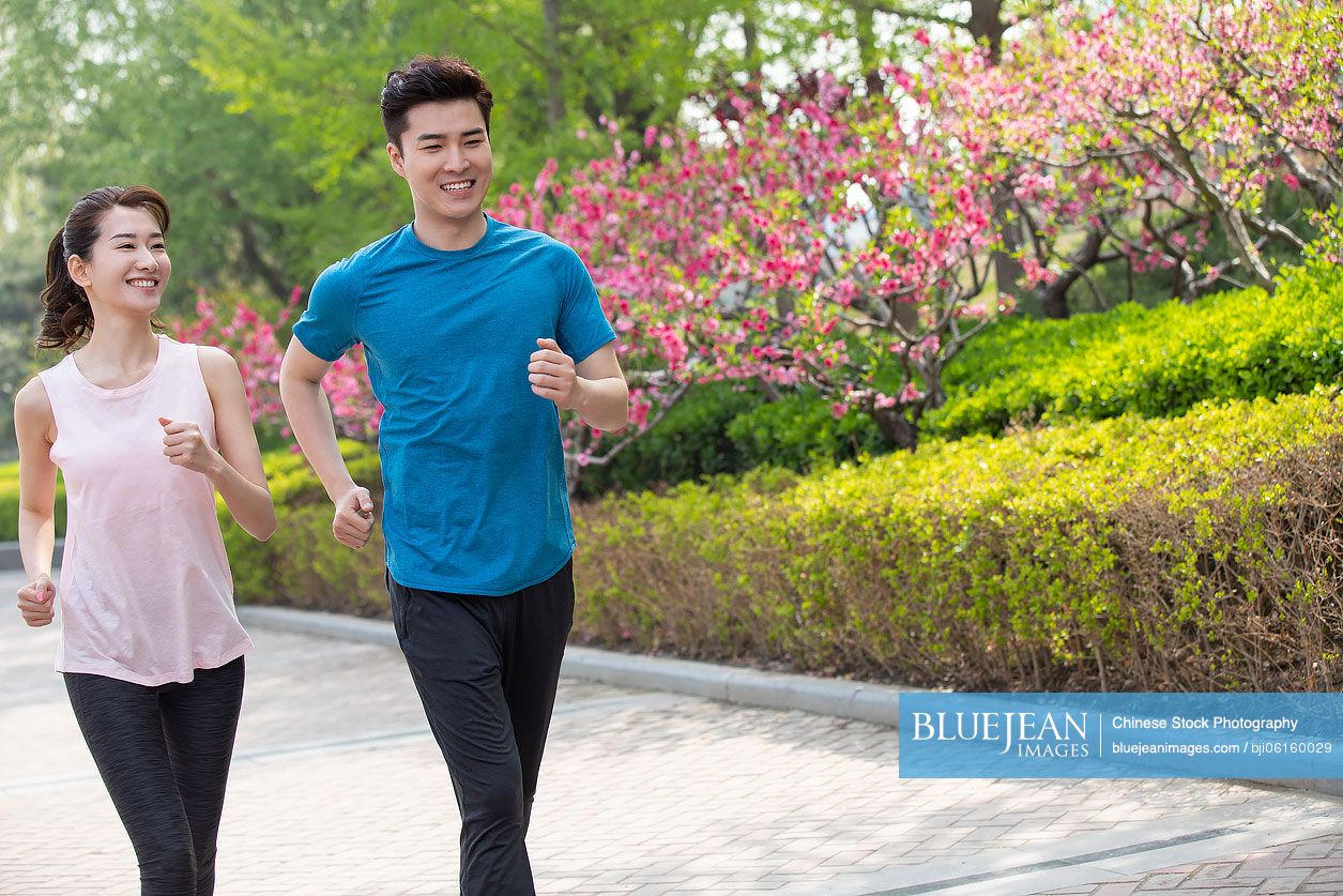 Happy young Chinese couple running in park