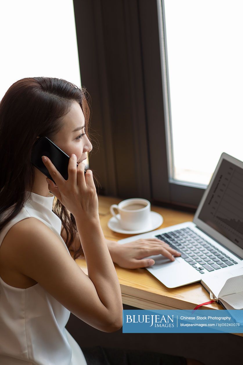 Chinese businesswoman talking on the phone in café