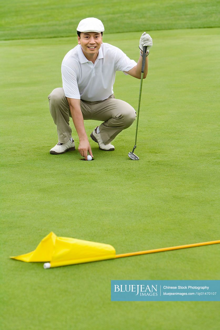 Portrait of a male Chinese golfer on green