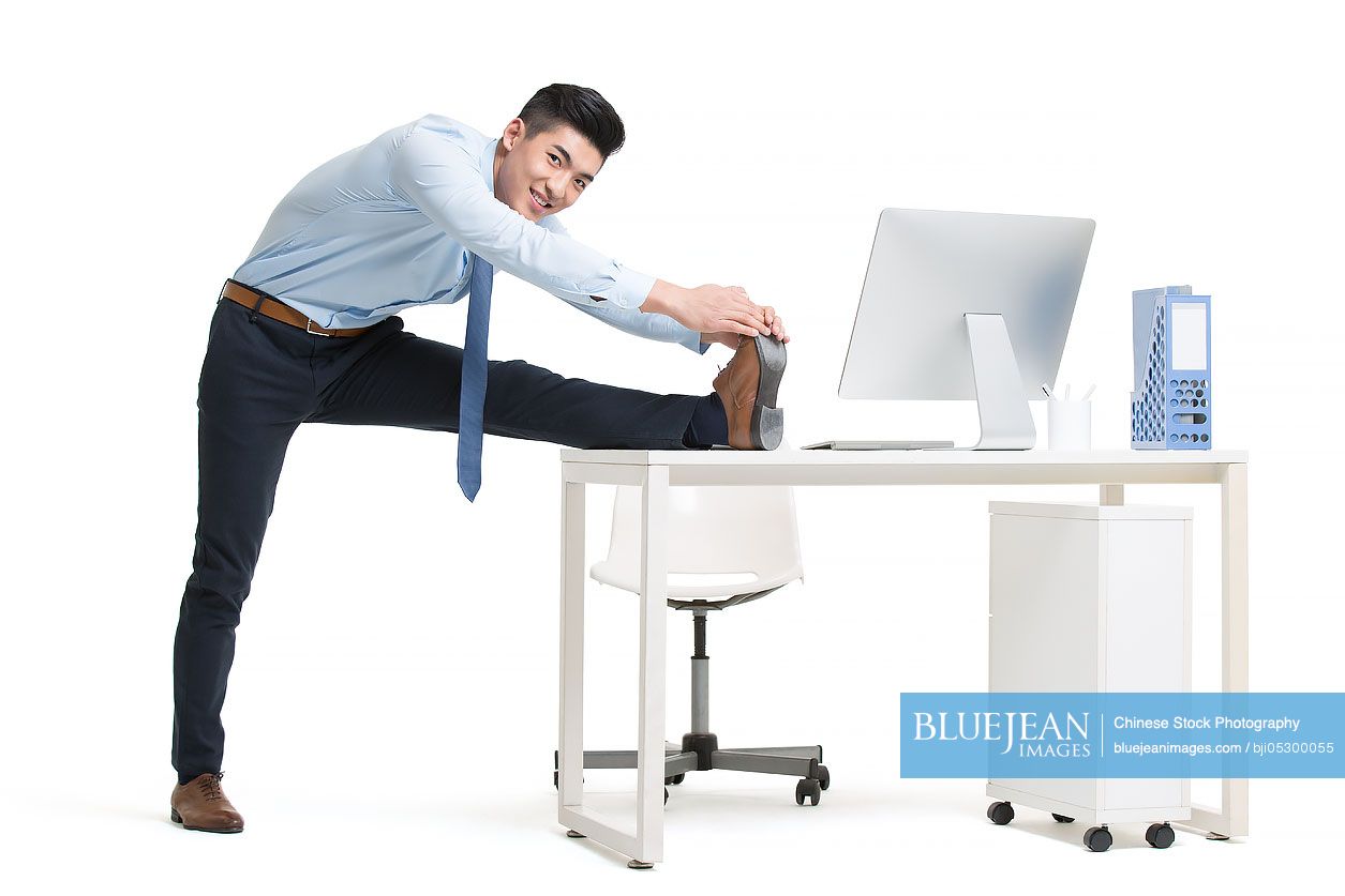 Young Chinese businessman exercising in office