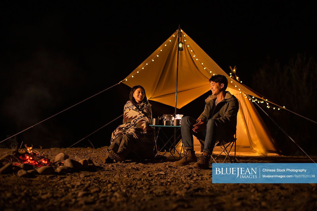 Happy young Chinese couple camping outdoors