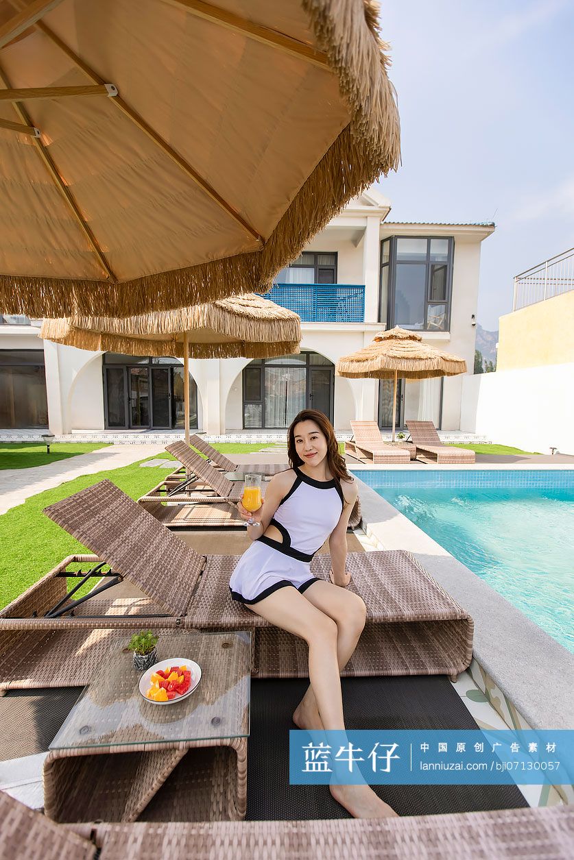 年轻女子在躺椅上喝果汁