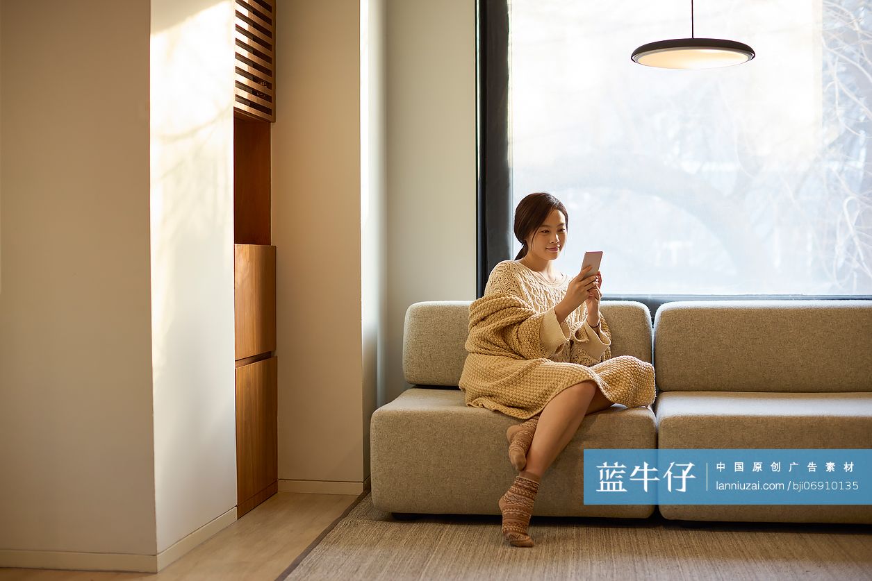 年轻女性坐沙发上玩手机