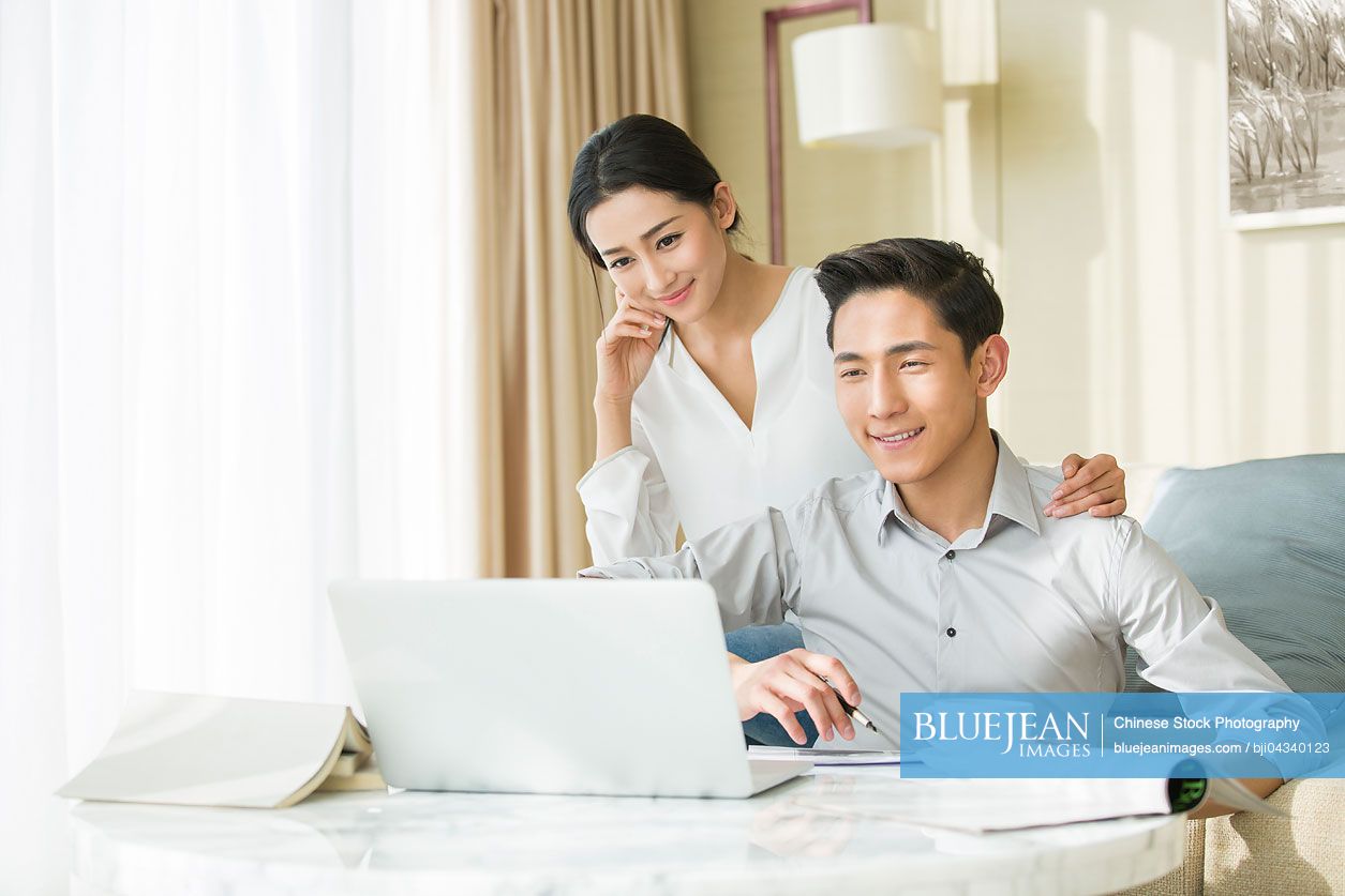Young Chinese couple looking at laptop