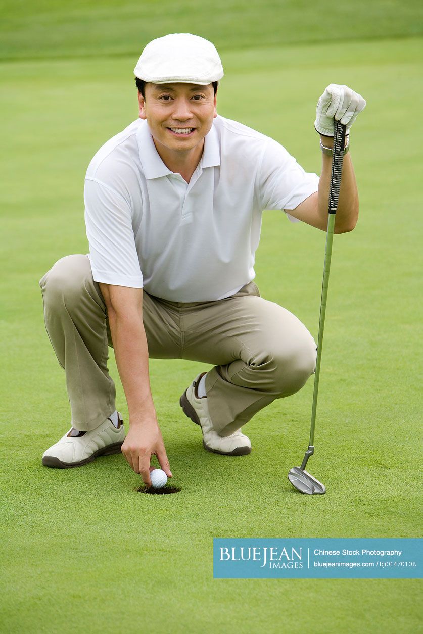 Portrait of a male Chinese golfer on green