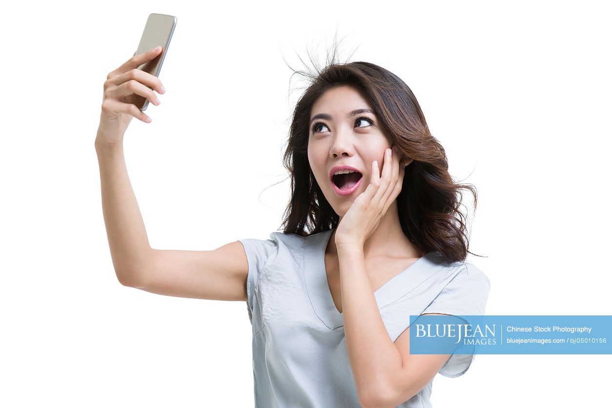 Young Chinese woman taking self portrait with smart phone