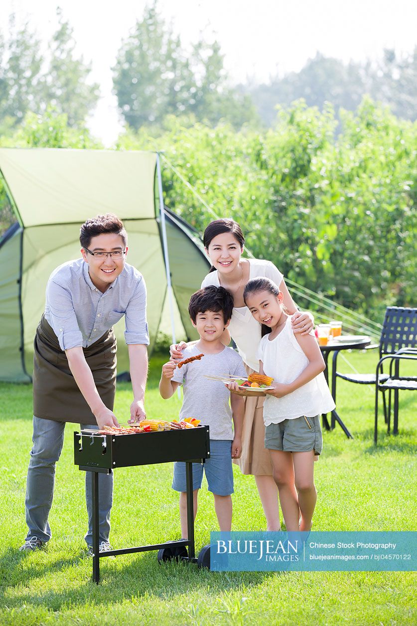 Young Chinese family barbecuing outdoors